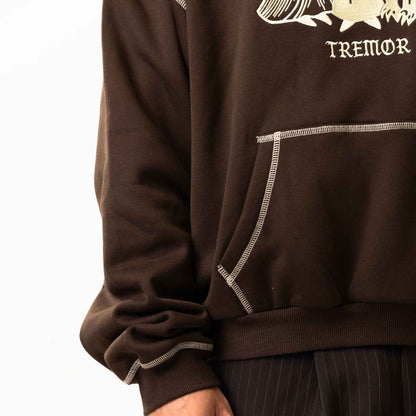Brown sweatshirt with white floral design and 'Tremor' text on a white background