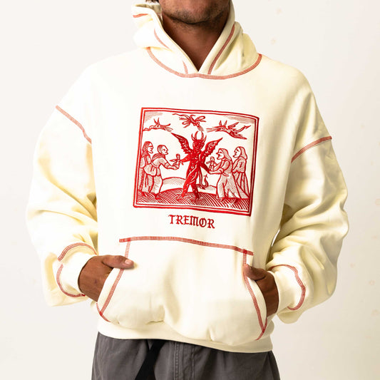Cream-colored hoodie with red graphic design and 'Tremor' text on a white background