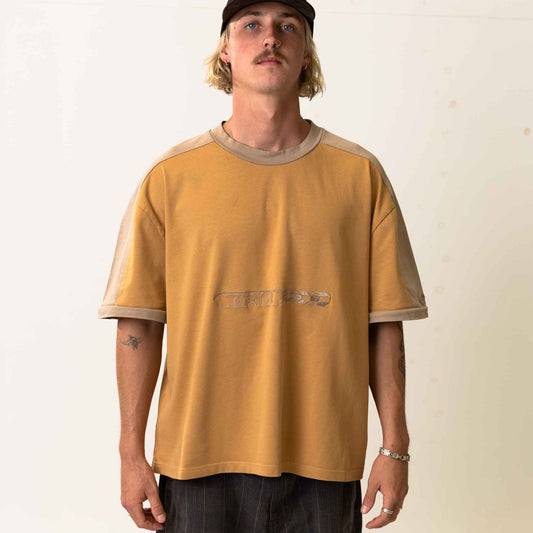 Man wearing a mustard yellow and beige t-shirt with a plain background